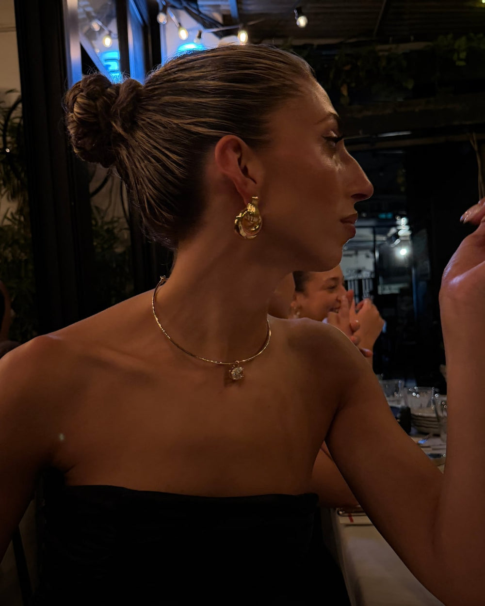 Gold necklace with a sparkling pendant worn on the neck